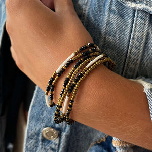 stretchy set of black, white, and brass beaded bracelets