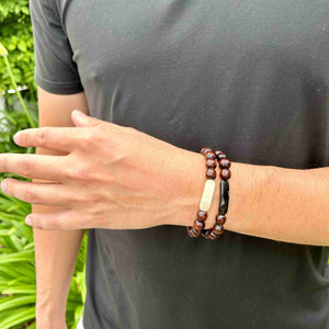  bracelet consists of dark wooden beads anchored by a strip of either dark or light ankole. 