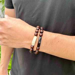  bracelet consists of dark wooden beads anchored by a strip of either dark or light ankole. 